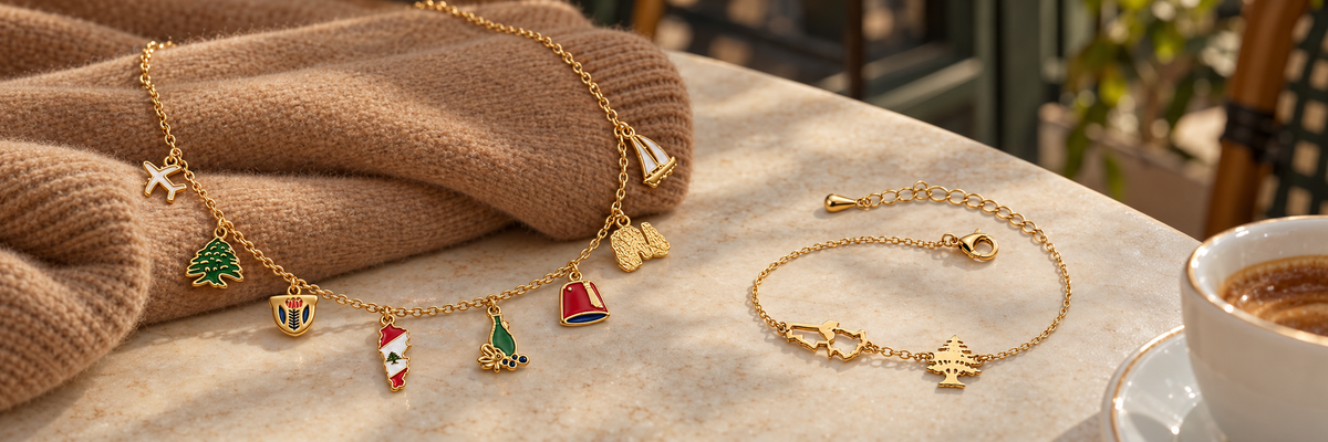 Lebanese heritage charm necklace and map-and-cedar bracelet on a café table with camel knitwear